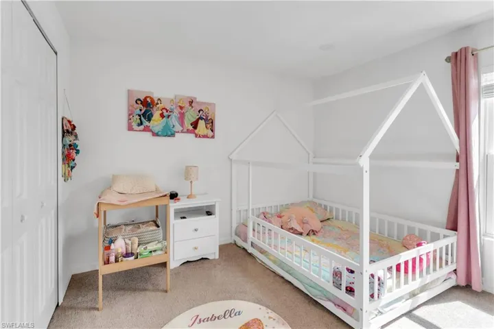 Bedroom featuring a closet, a crib, and light colored carpet