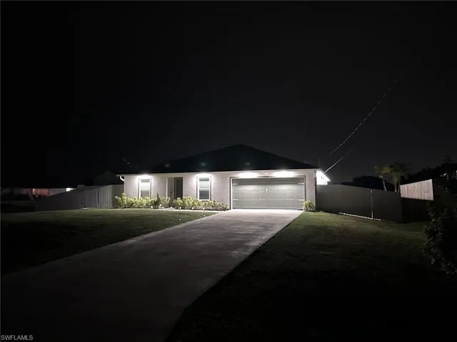 View of front of home featuring a garage with lighs at night