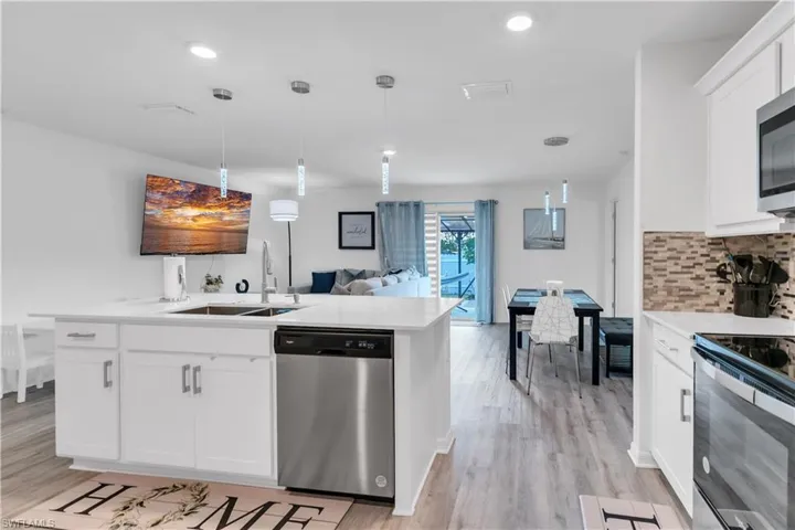 Kitchen featuring backsplash, light hardwood / wood-style flooring, dishwasher, range with electric cooktop, and white cabinets