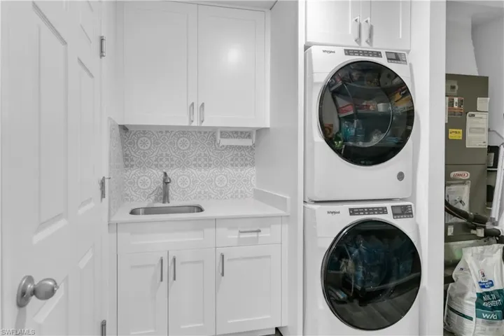 Laundry room with sink, stacked washer and dryer, and cabinets