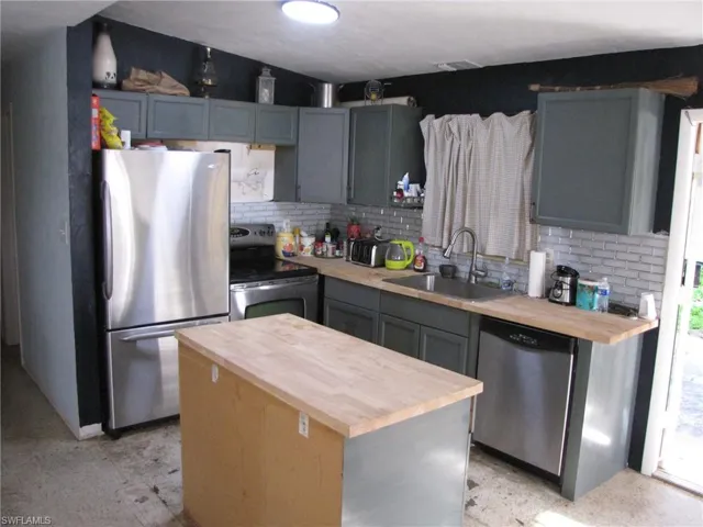 Kitchen featuring wooden counters, a center island, sink, and stainless steel appliances