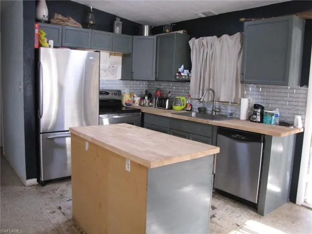 Kitchen featuring stainless steel appliances, sink, wood counters, and a center island