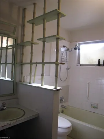 Full bathroom with tiled shower / bath combo, vanity, and toilet
