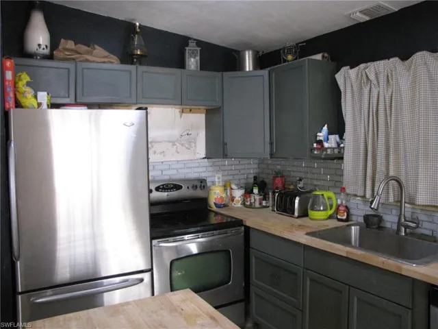 Kitchen with decorative backsplash, stainless steel appliances, butcher block countertops, and sink