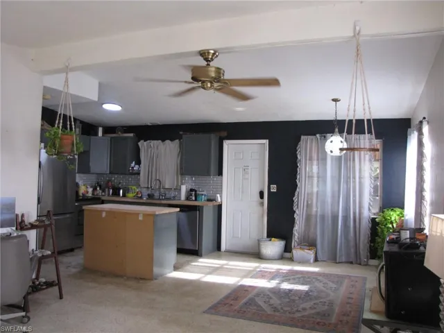 Kitchen featuring a kitchen island, ceiling fan, appliances with stainless steel finishes, decorative backsplash, and sink