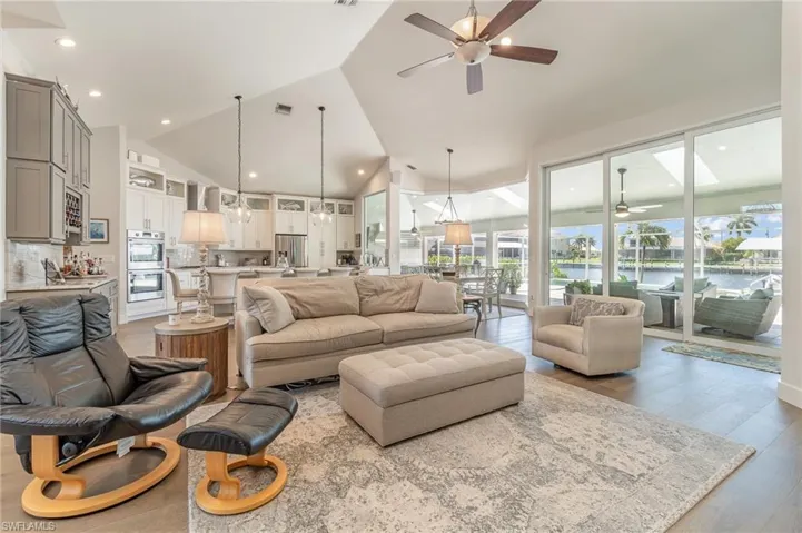Living room with light hardwood / wood-style floors, lofted ceiling, a water view, and ceiling fan