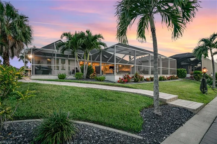 Back house at dusk with a yard and screen enclosure