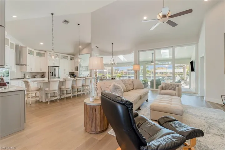 Living room with light hardwood / wood-style flooring, high vaulted ceiling, and ceiling fan