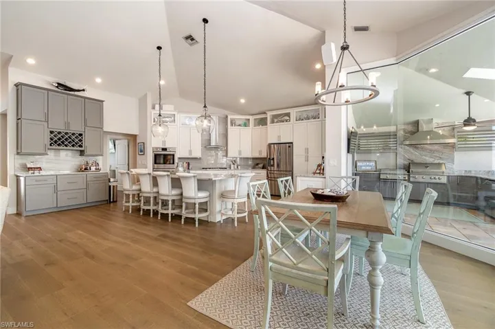 Dining area with vaulted ceiling, wood-type flooring, and ceiling fan with notable chandelier