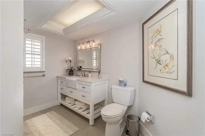 Bathroom featuring vanity, toilet, tile patterned floors, and a raised ceiling