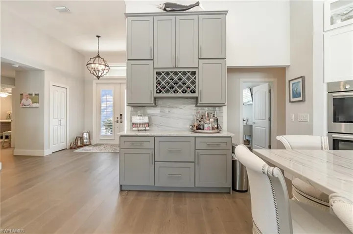 Kitchen wine bar featuring light hardwood / wood-style floors, gray cabinetry, and pendant lighting