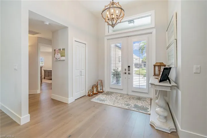 Entryway with french doors, light hardwood / wood-style floors, and a notable chandelier
