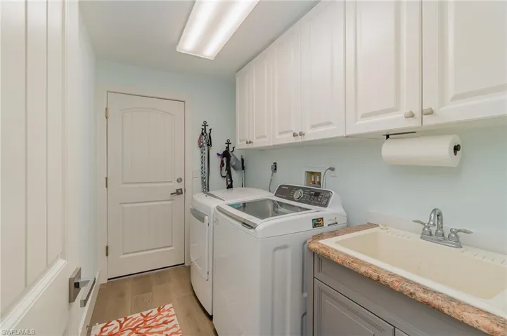 Laundry area featuring light hardwood / wood-style floors, cabinets, sink, and washing machine and clothes dryer