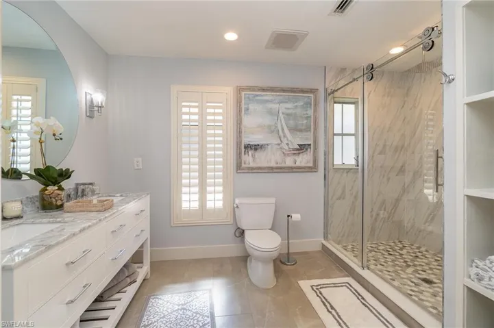 Bathroom featuring toilet, plenty of natural light, and a shower with door