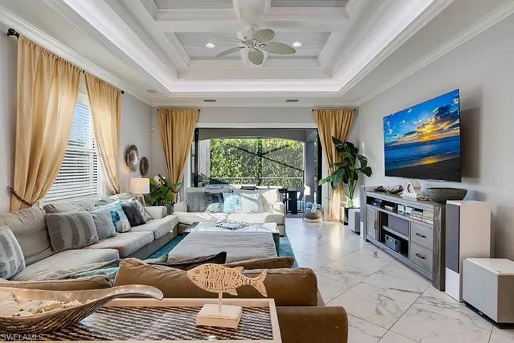 Living room with crown molding, light marble finish flooring, a ceiling fan, coffered ceiling, and recessed lighting