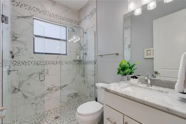 Bathroom with vanity and a marble finish shower