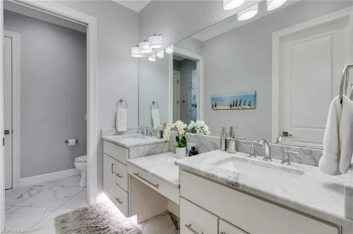 Bathroom with vanity, ornamental molding, and light marble finish flooring