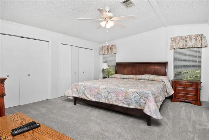 Bedroom with multiple closets, a ceiling fan, and light carpet