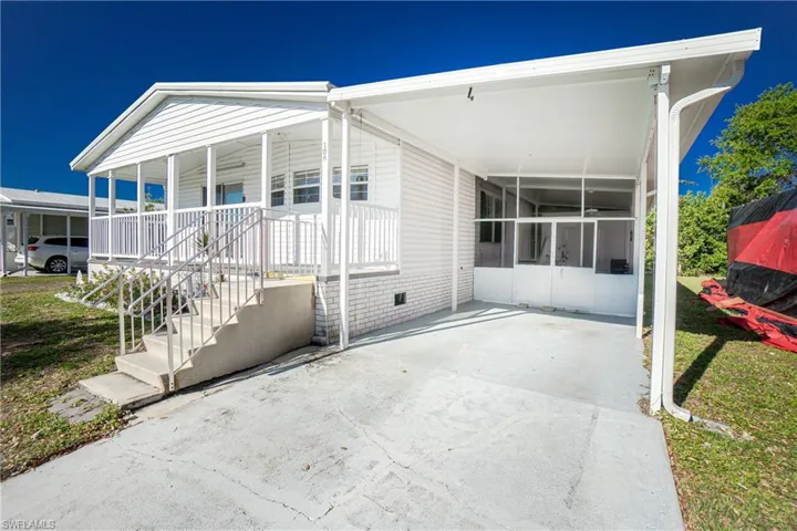 Back of property featuring a carport, a lawn, and a patio
