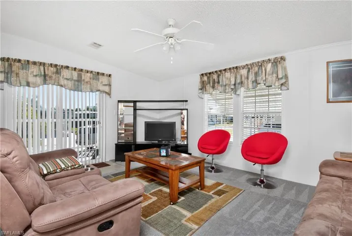 Living area featuring ceiling fan, carpet floors, and a textured ceiling