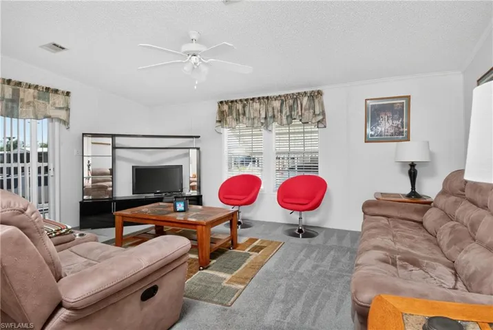 Living area featuring carpet flooring, a ceiling fan, and a textured ceiling