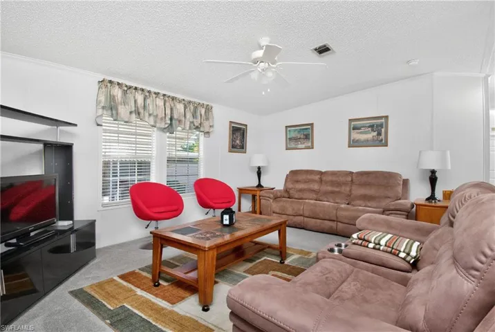 Carpeted living room featuring a ceiling fan
