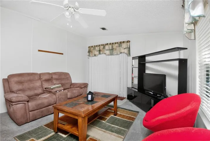 Carpeted living room with a textured ceiling and a ceiling fan