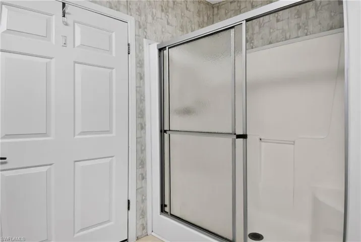 Full bathroom featuring a shower stall and wallpapered walls
