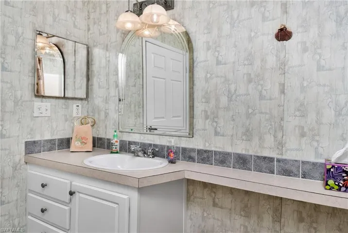 Bathroom with vanity and wallpapered walls
