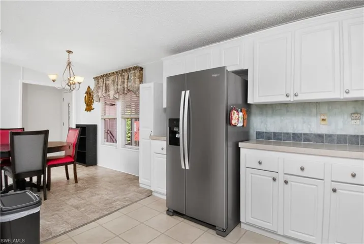 Kitchen with stainless steel fridge with ice dispenser, white cabinetry, light countertops, and a textured ceiling
