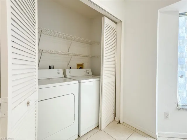 Laundry area with light tile patterned flooring and washer and clothes dryer