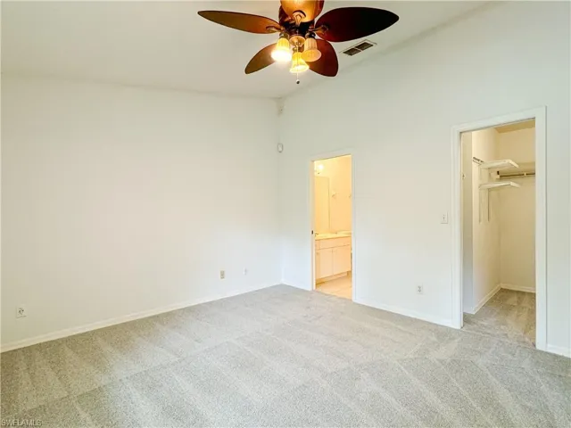 Unfurnished bedroom featuring a high ceiling, ceiling fan, a spacious closet, light colored carpet, and a closet