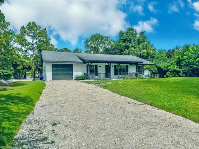 Ranch-style home featuring a porch, a garage, and a front yard