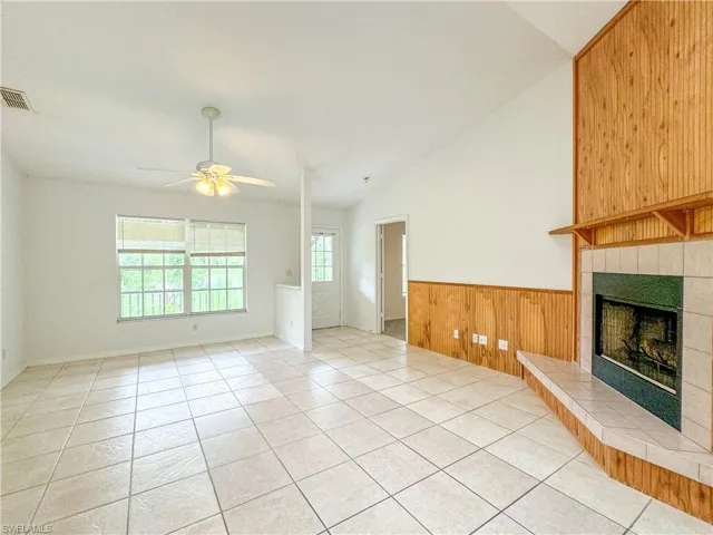 Unfurnished living room with light tile patterned flooring, a fireplace, ceiling fan, and a healthy amount of sunlight