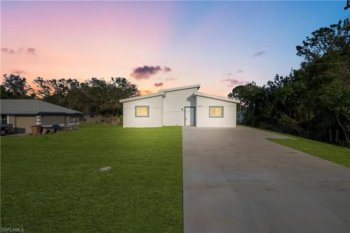 View of front of home featuring concrete driveway, stucco siding, and a yard