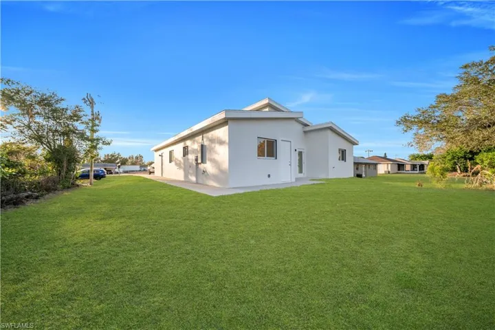 Rear view of house featuring stucco siding and a lawn
