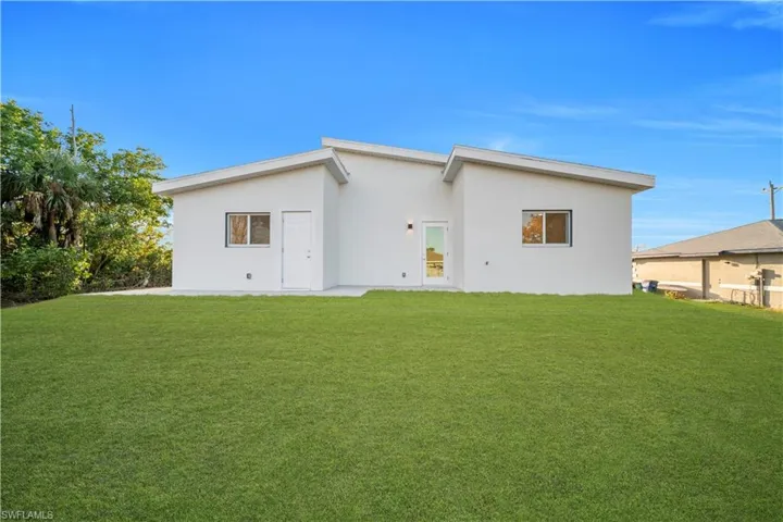 Back of property with stucco siding and a yard