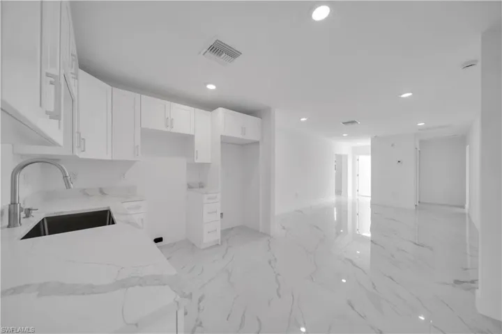 Kitchen with white cabinetry, recessed lighting, and light stone counters