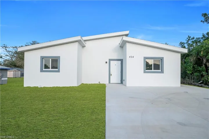 View of front of property with a front yard, stucco siding, and driveway