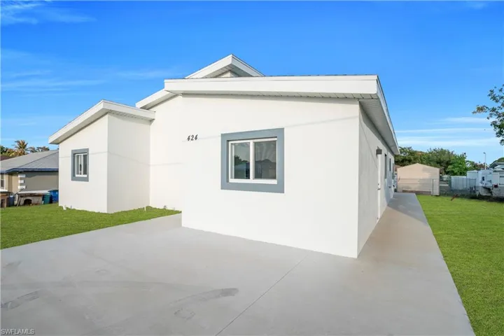 Back of house with a yard and stucco siding