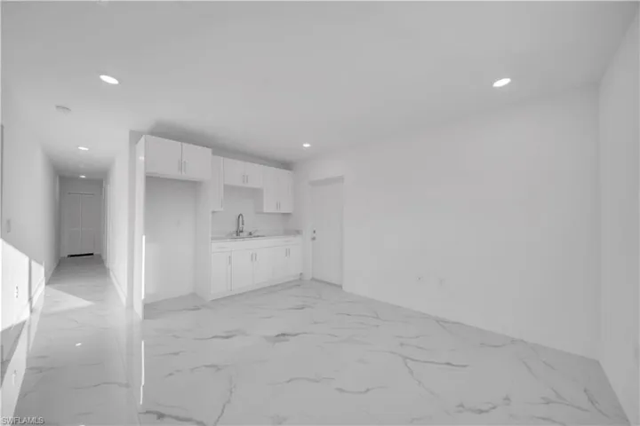 Kitchen with stainless steel appliances, recessed lighting, white cabinets, and light stone countertops