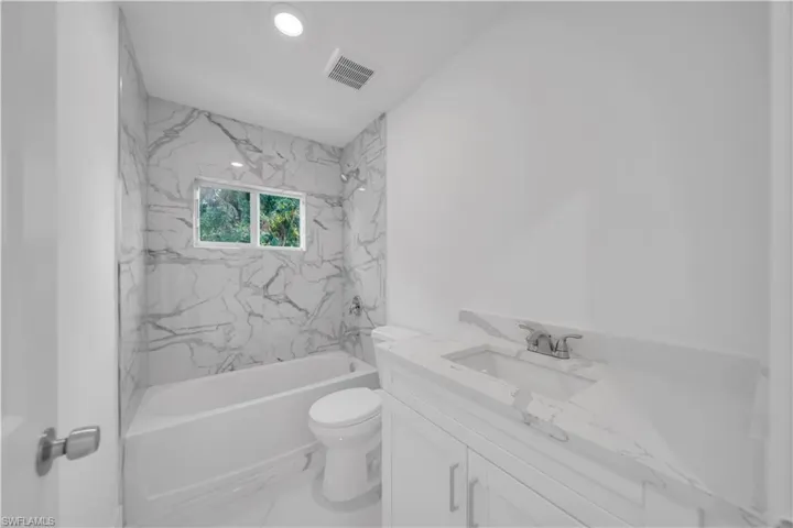 Kitchen featuring light marble finish flooring, white cabinetry, light stone counters, and recessed lighting