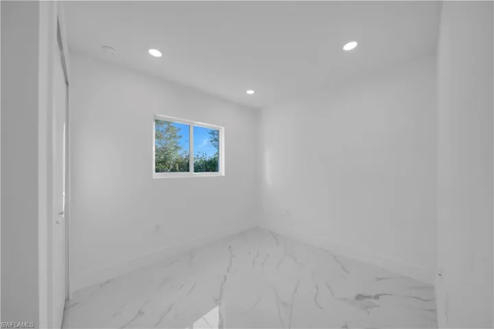 Kitchen with white cabinetry, recessed lighting, light countertops, and light marble finish flooring