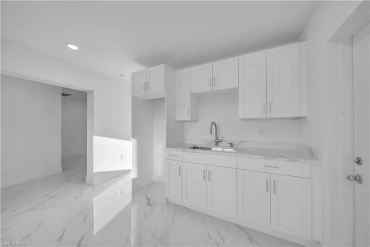 Kitchen with white cabinets, light countertops, recessed lighting, and light marble finish floors