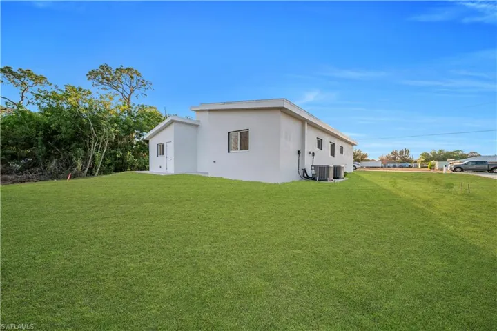 View of side of property with a lawn and stucco siding