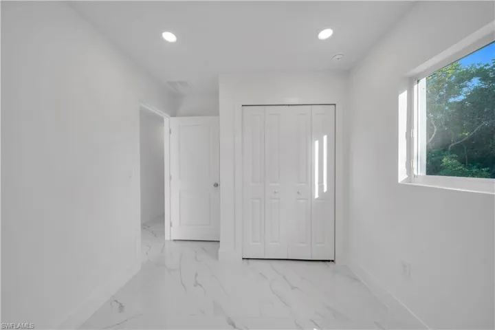 Kitchen featuring recessed lighting, white cabinetry, light marble finish floors, and light stone counters