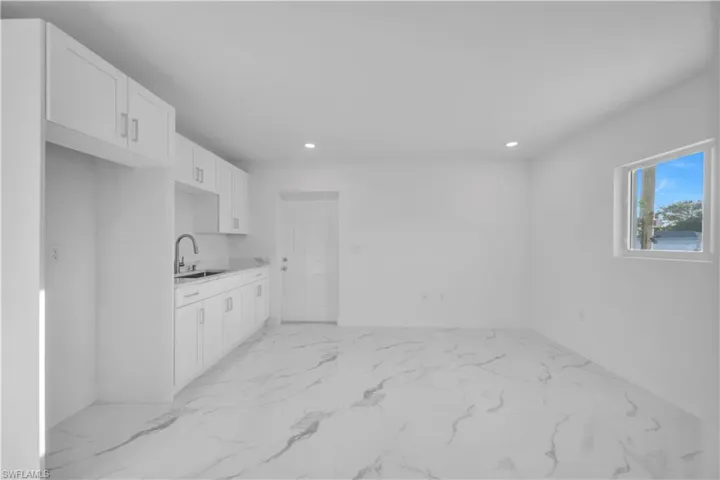 Kitchen featuring stainless steel appliances, white cabinets, recessed lighting, and light marble finish floors