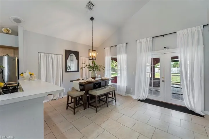 Dining space with plenty of natural light, light tile patterned floors, french doors, and an inviting chandelier