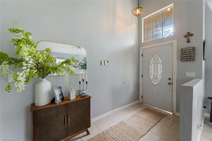 Foyer with light tile patterned floors and a towering ceiling