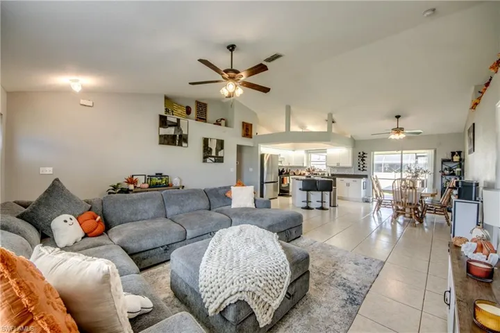 Living room with light tile patterned flooring, ceiling fan, and high vaulted ceiling